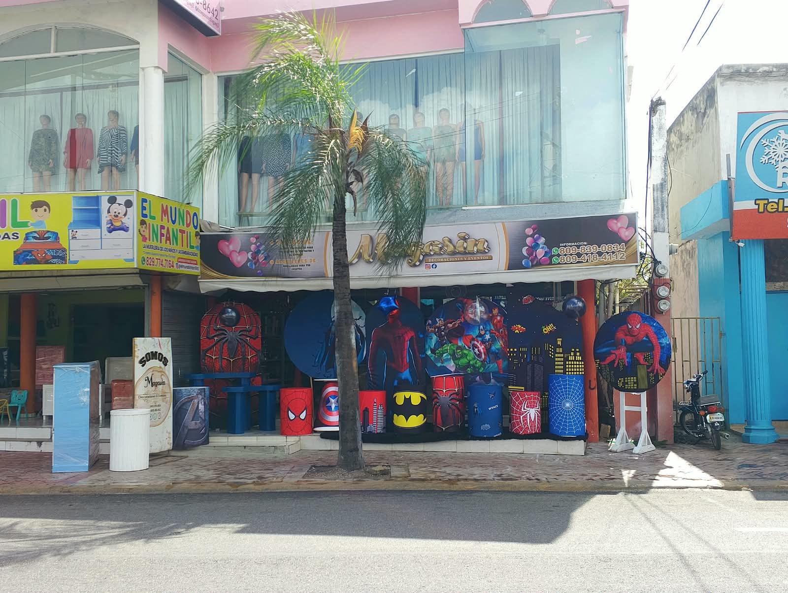 Vista de la calle con la tienda Magasin Victoria en Higüey y su vitrina de decoración de superhéroes