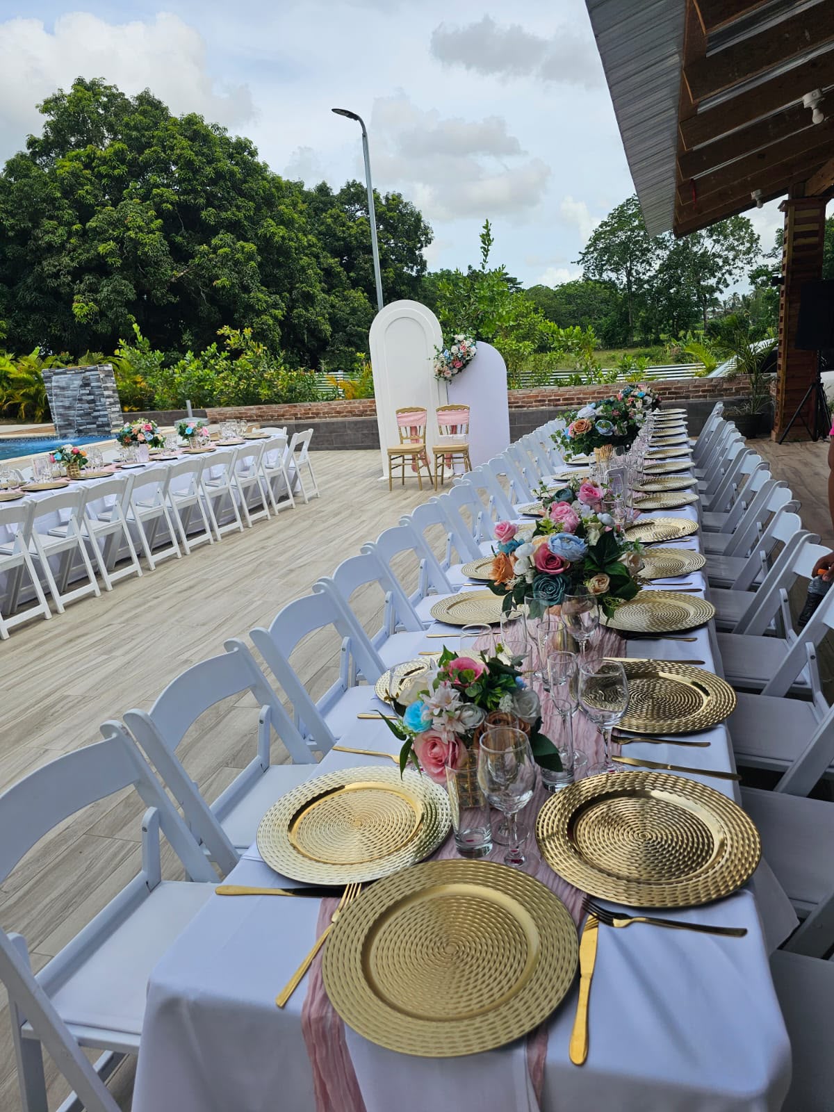 Mesa imperial con bajoplatos dorados y flores pastel, montada por Magasin Victoria para una boda en Higüey