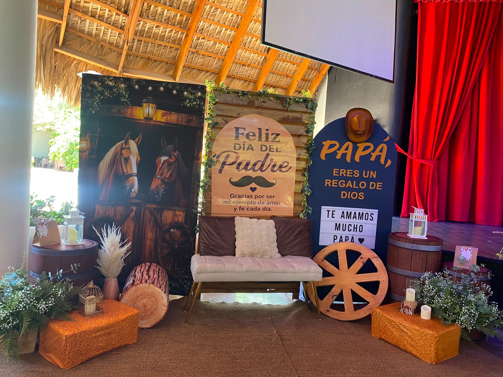 Decoración rústica para el Día del Padre con letreros 'Feliz Día del Padre', banco, barriles, pacas y rueda de carreta en Higüey