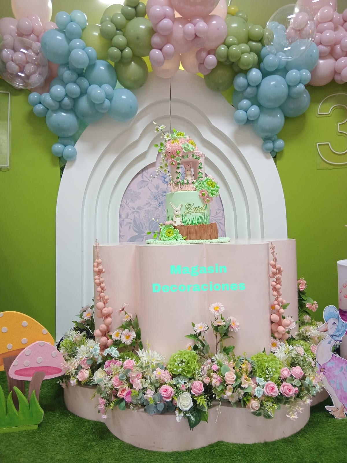 Pastel de conejito sobre pedestal rosado con flores y arco de globos pastel, decoración de cumpleaños de Magasin Victoria