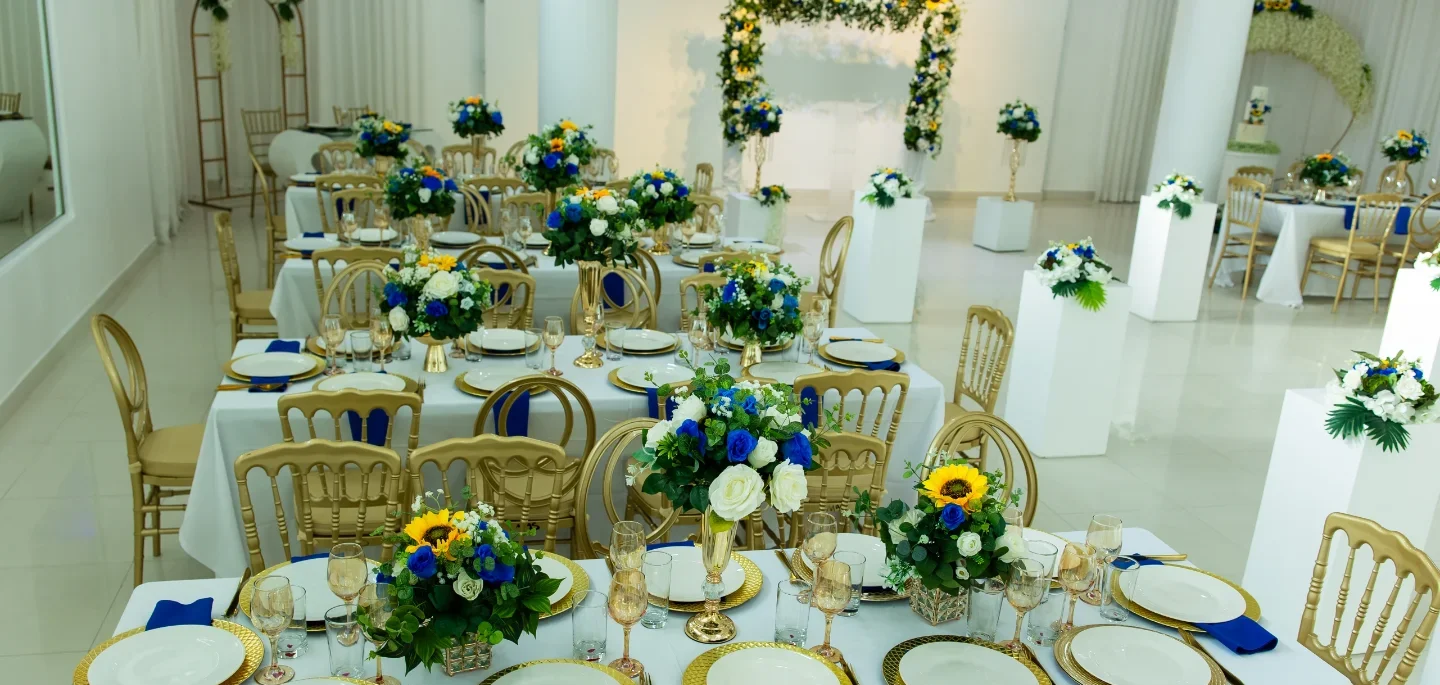 Salón de boda montado por Magasin Victoria, mesas con centros florales azul y girasoles, sillas doradas